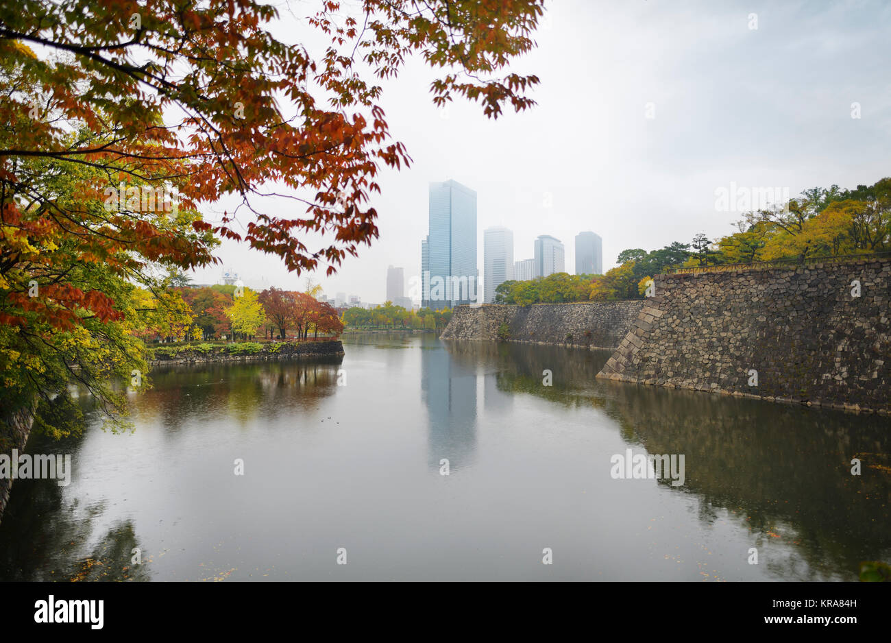 Osaka downtown Chuo-ku financial distric high-rise towers, Crystal tower and other buildings view from Osaka Castle Park moat in colorful autumn foggy Stock Photo