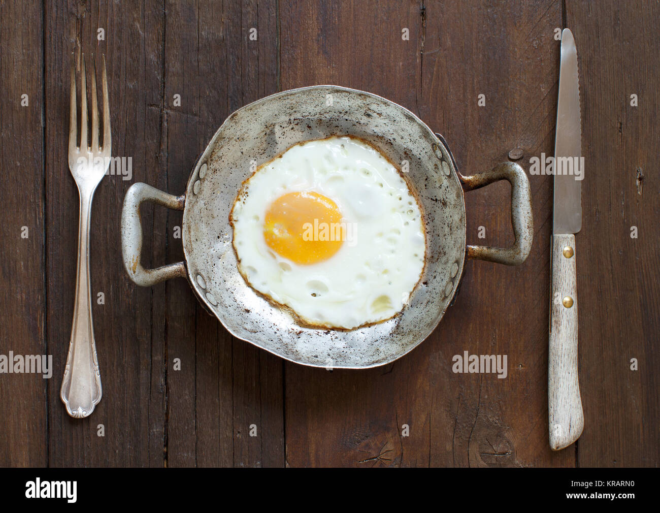 Fried egg in a old frying pan with fork and knife Stock Photo - Alamy