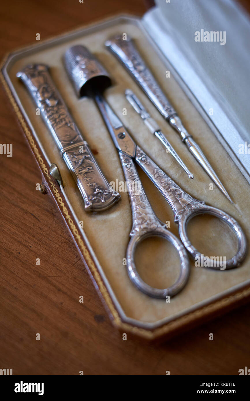 An antique vintage silver embroidery sewing set kit with scissors, thimble, threader, awl and