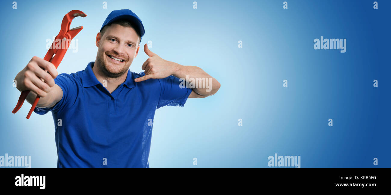 plumbing services - plumber with wrench showing phone call gesture on blue background with copy space Stock Photo