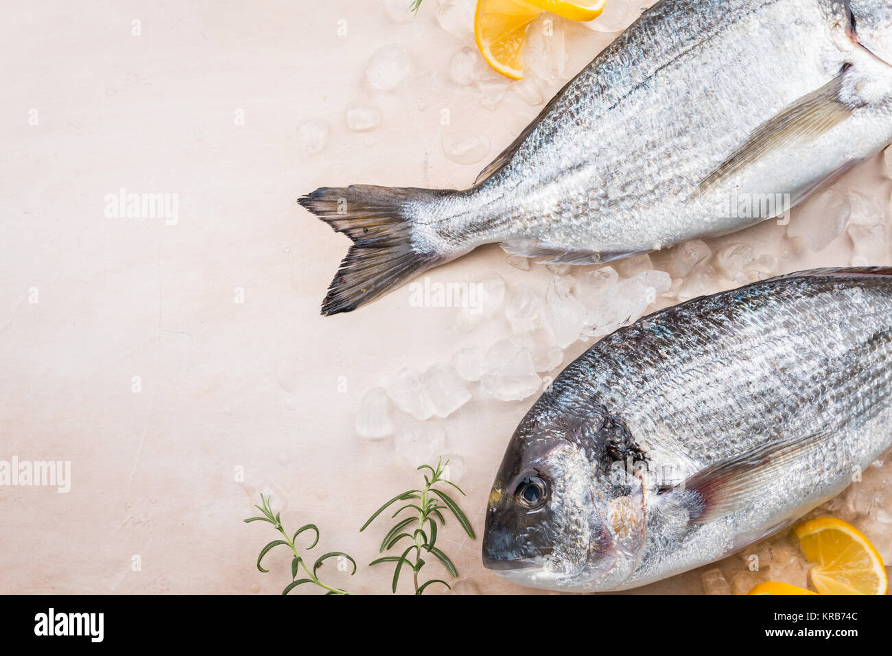 Fresh uncooked dorado or sea bream fish with ice over beige background, top view Stock Photo