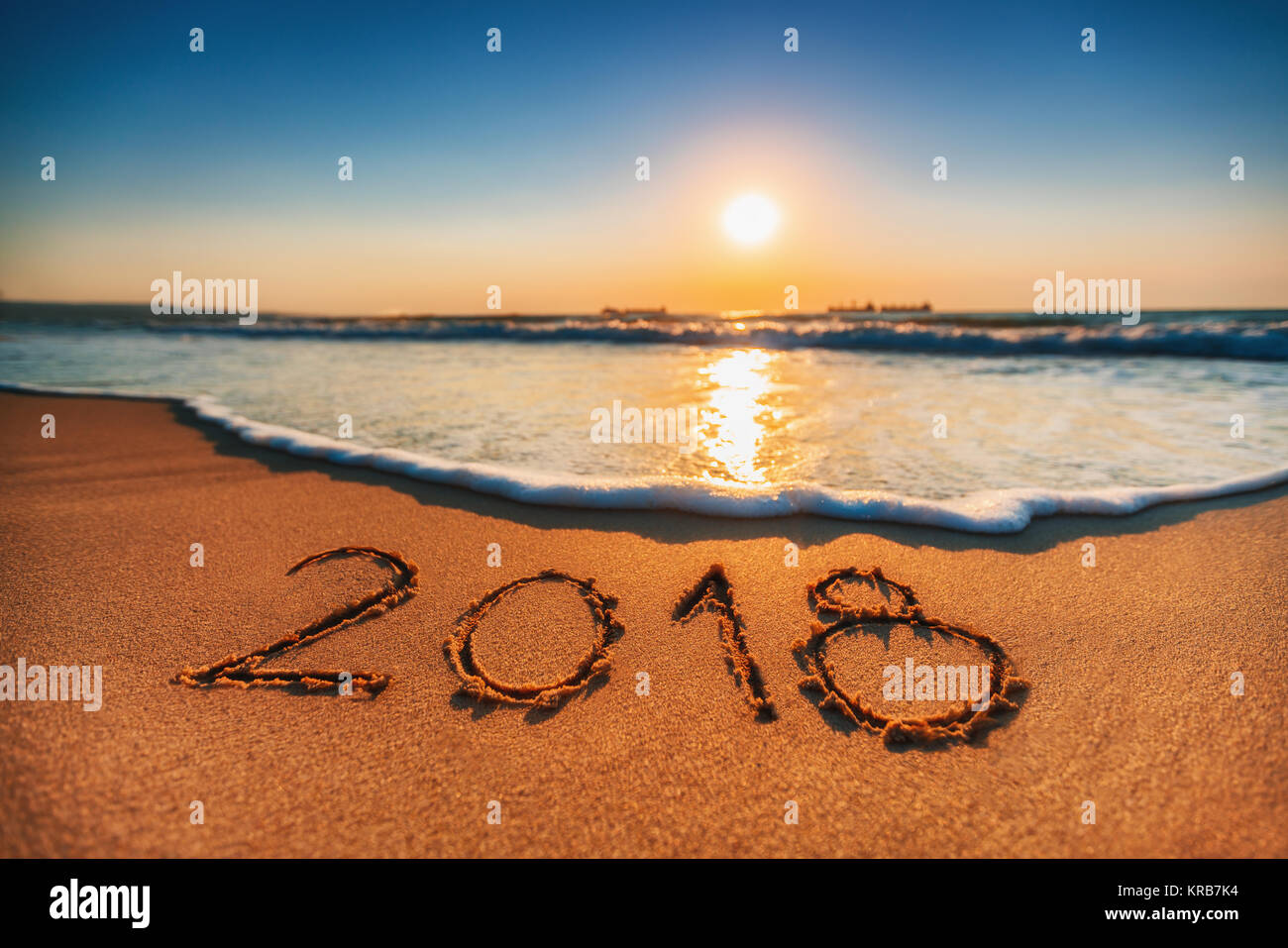 Happy New Year 2018 concept, lettering on the beach. Sea sunrise. Stock Photo