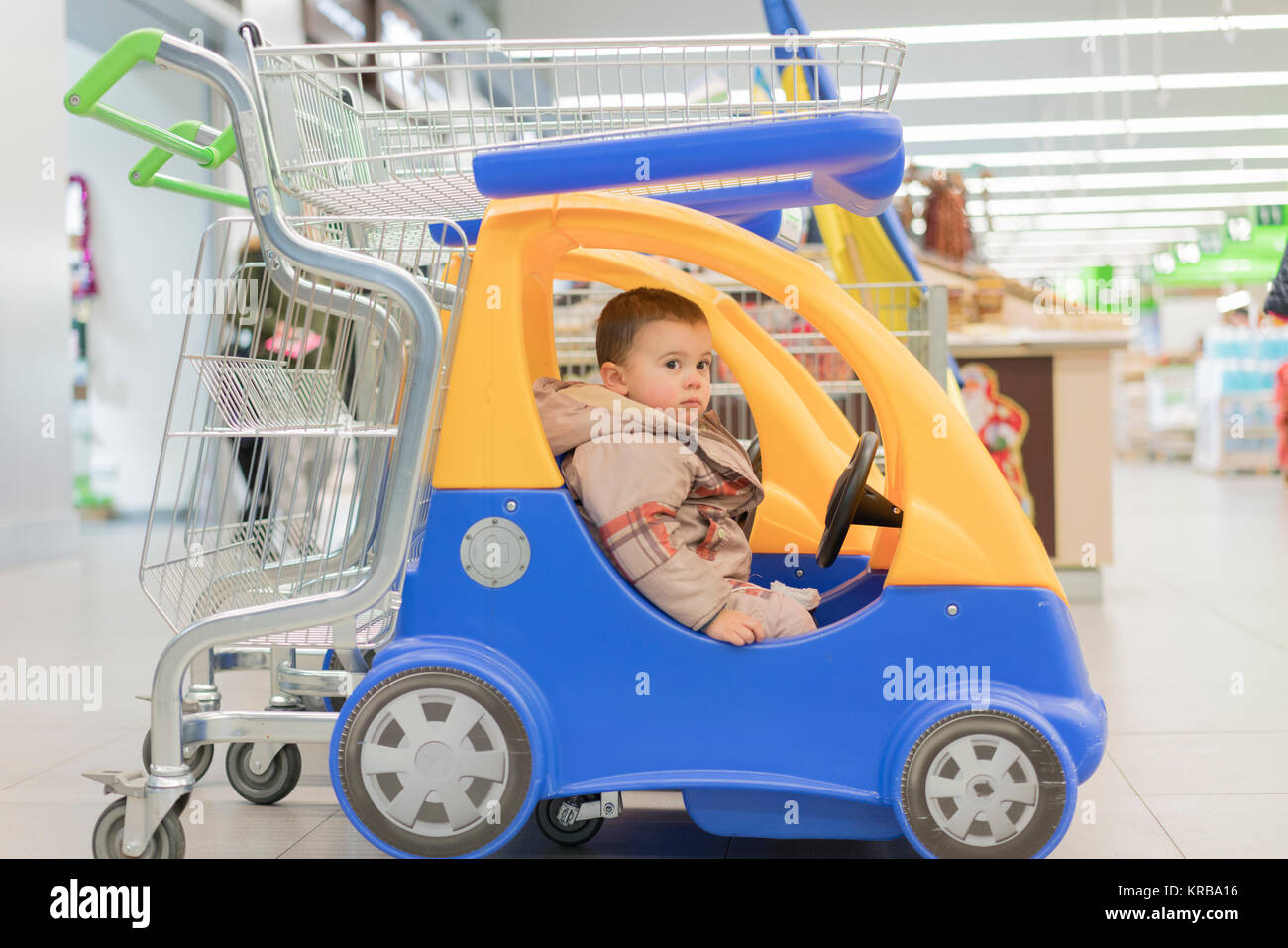 Cute toddler boy sitting in the shopping cart in a food store or a supermarket Stock Photo