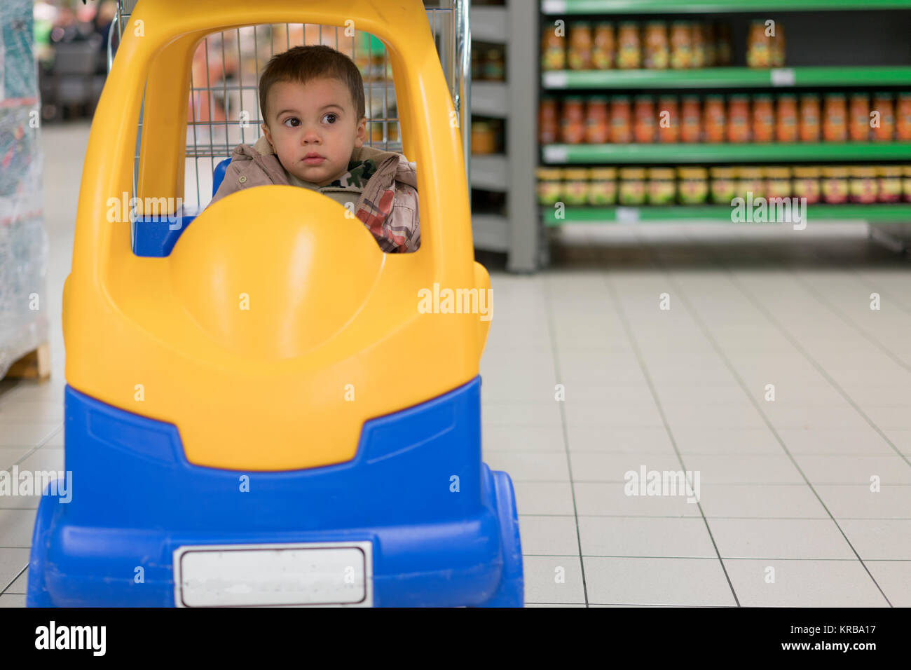 Toddler boy in a cart in the supermarket Stock Photo