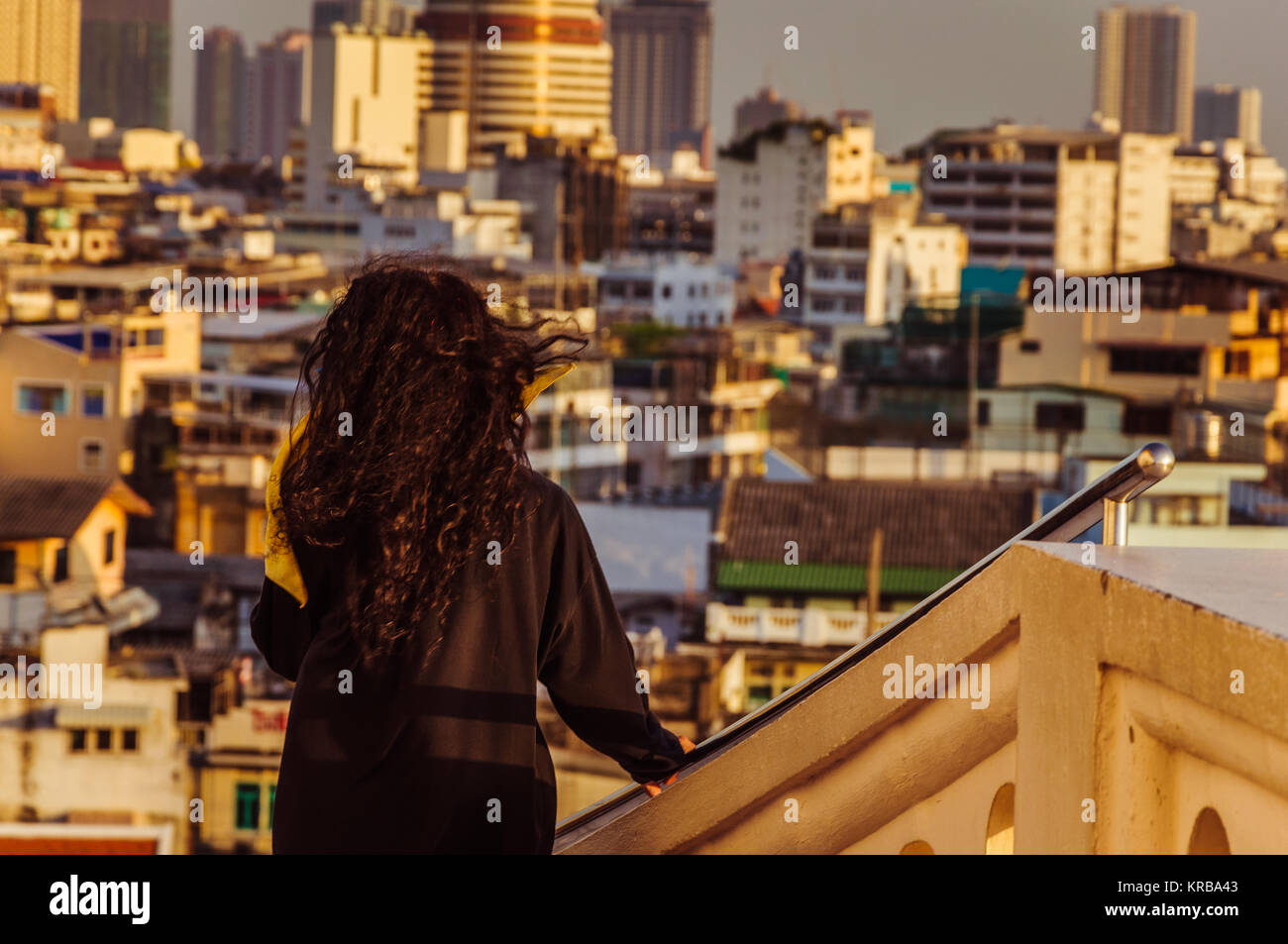 Young brunette going down with Bangkok skyline on the background Stock Photo