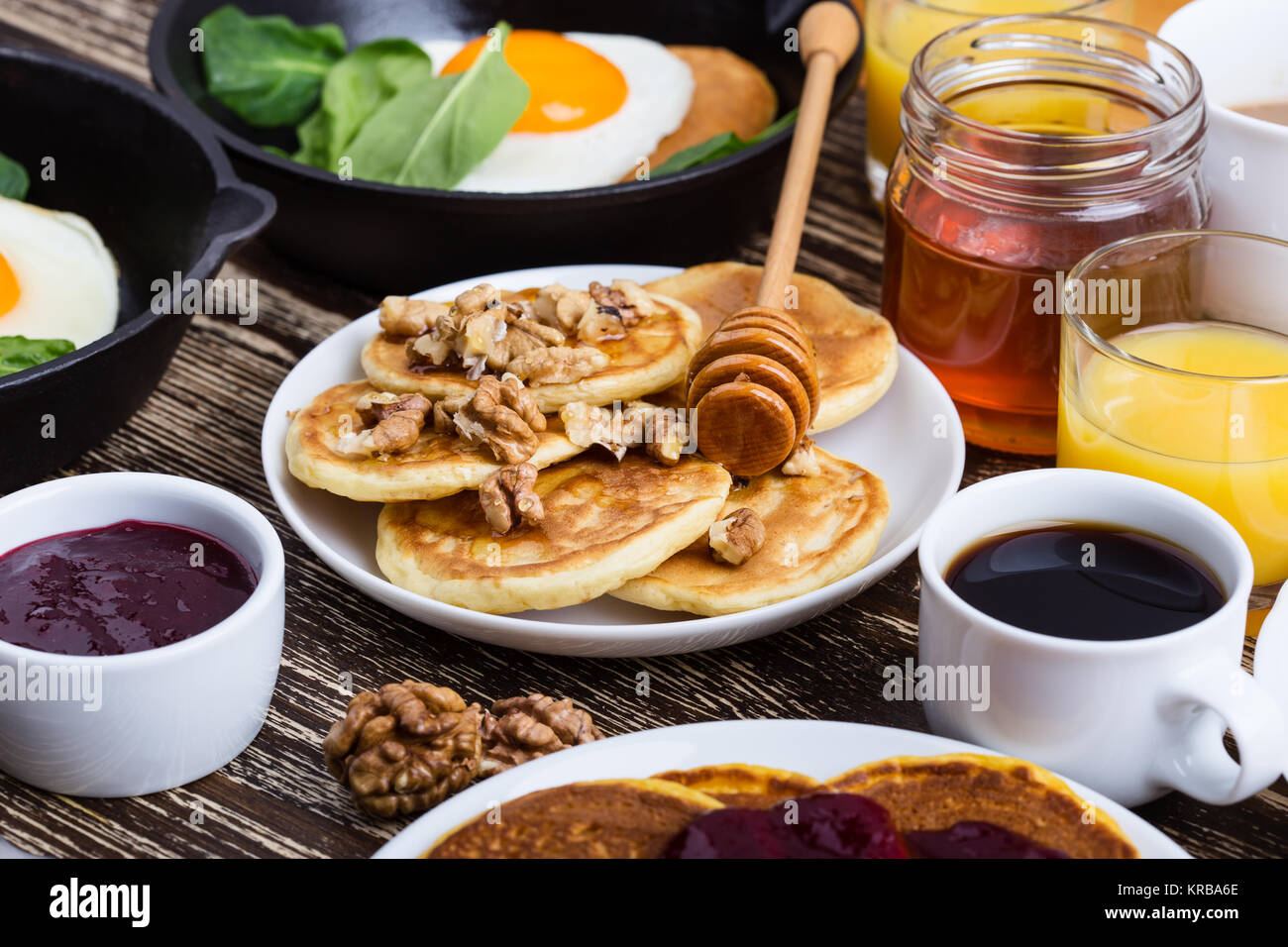 Valentine's day breakfast or brunch. Homemade  heart shape fried egg and pancake in cast iron skillet  with spinach,  pancakes with honey and walnuts, Stock Photo