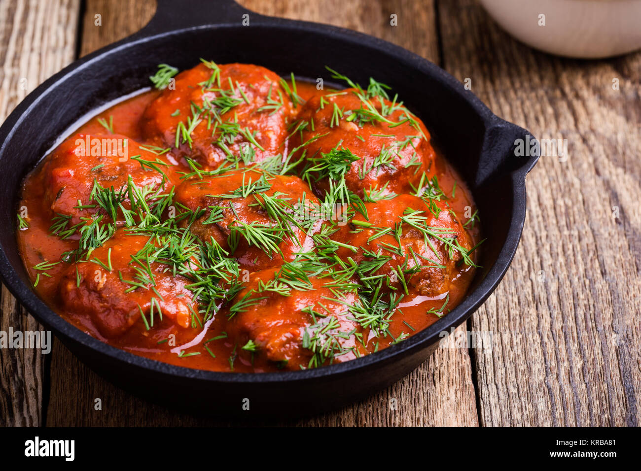 Beef meatballs in cast iron skillet with tomato sauce served with fresh