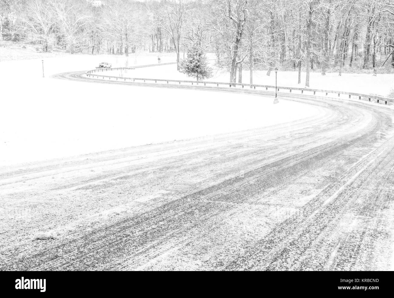 Black and white winter rural scenery with the road covered in snow and ...