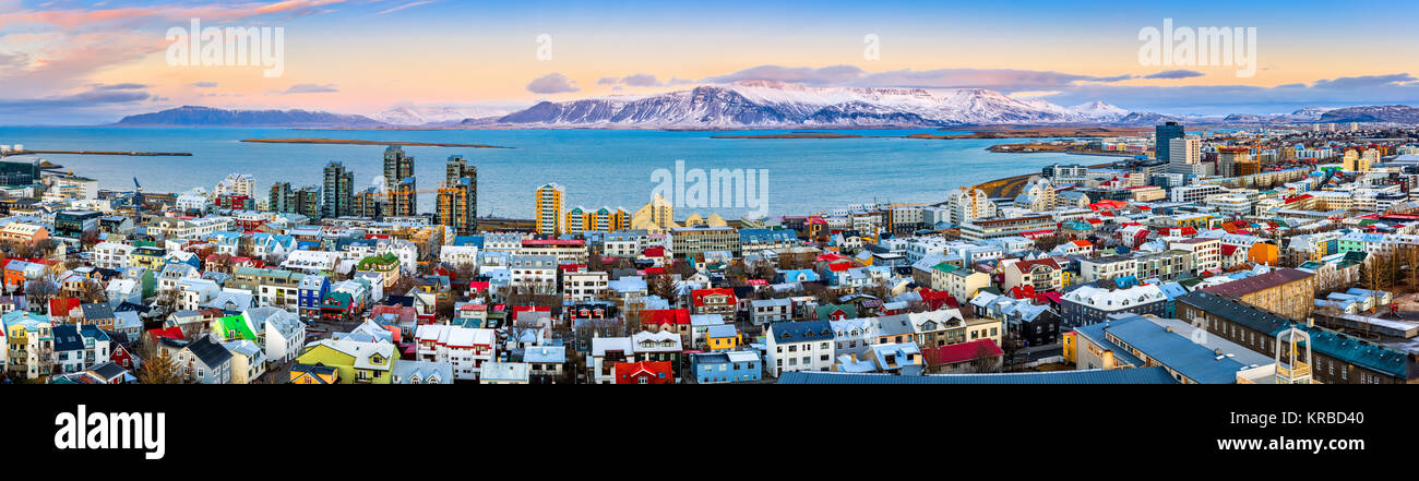 Aerial panorama of downtown Reykjavik at sunset with colorful houses and snowy mountains in the background Stock Photo