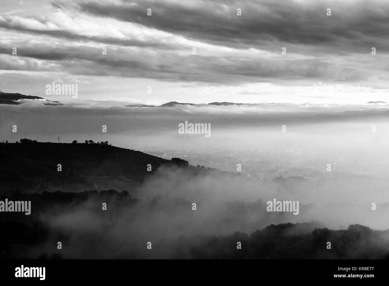 Umbria valley in autumn filled by mist, with emerging hills and trees Stock Photo