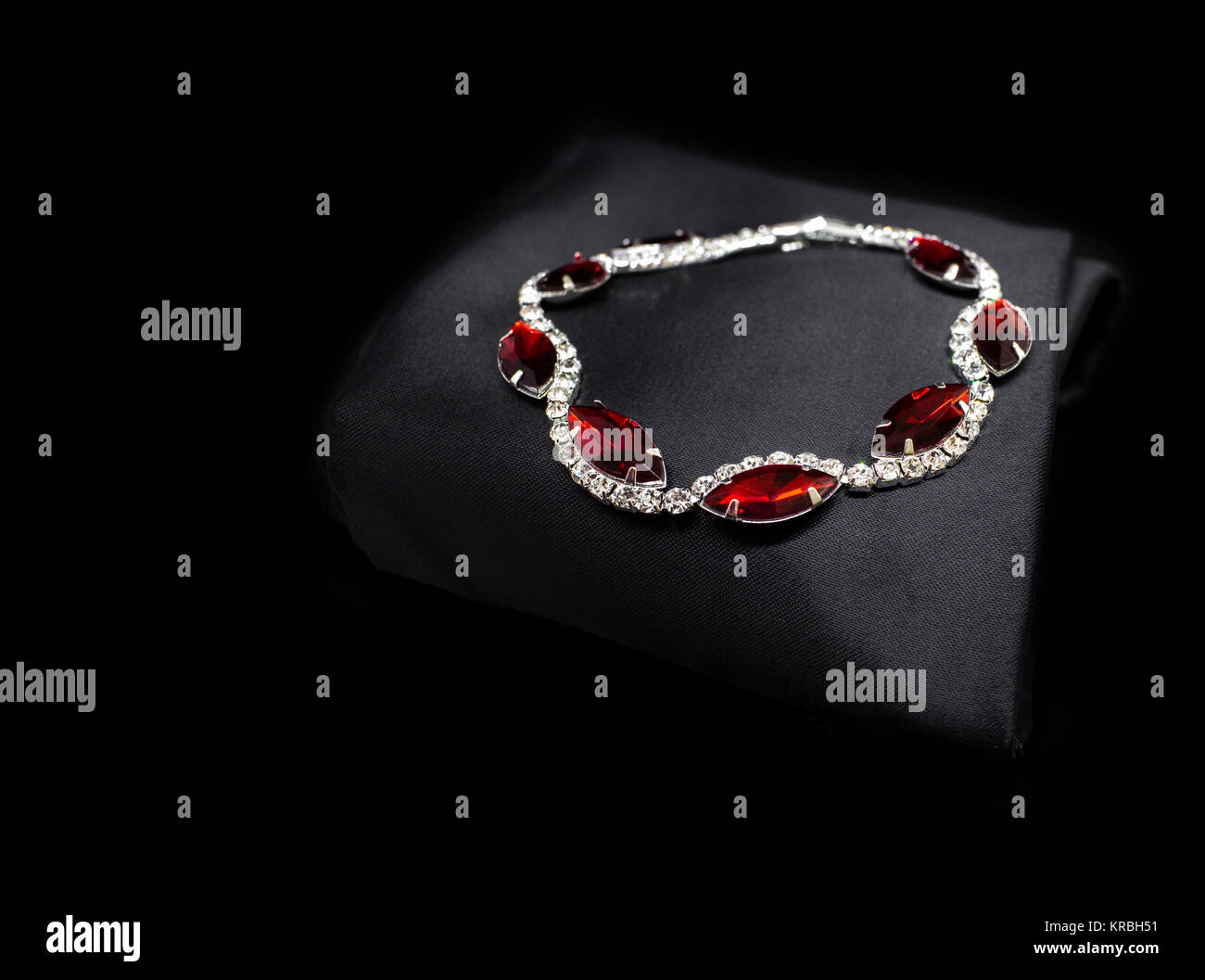 Jewellery silver ruby diamonds bracelet isolated on black cloth background Stock Photo