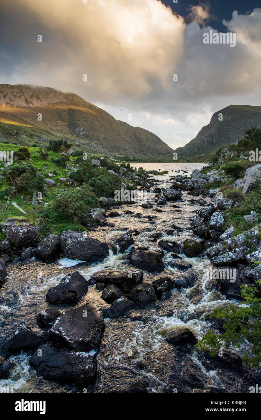 The River Loe tumbles through rocks from the Black Lake in the Gap of Dunloe mountain pass, seen from the Wishing Bridge, in Ireland's County Kerry. Stock Photo