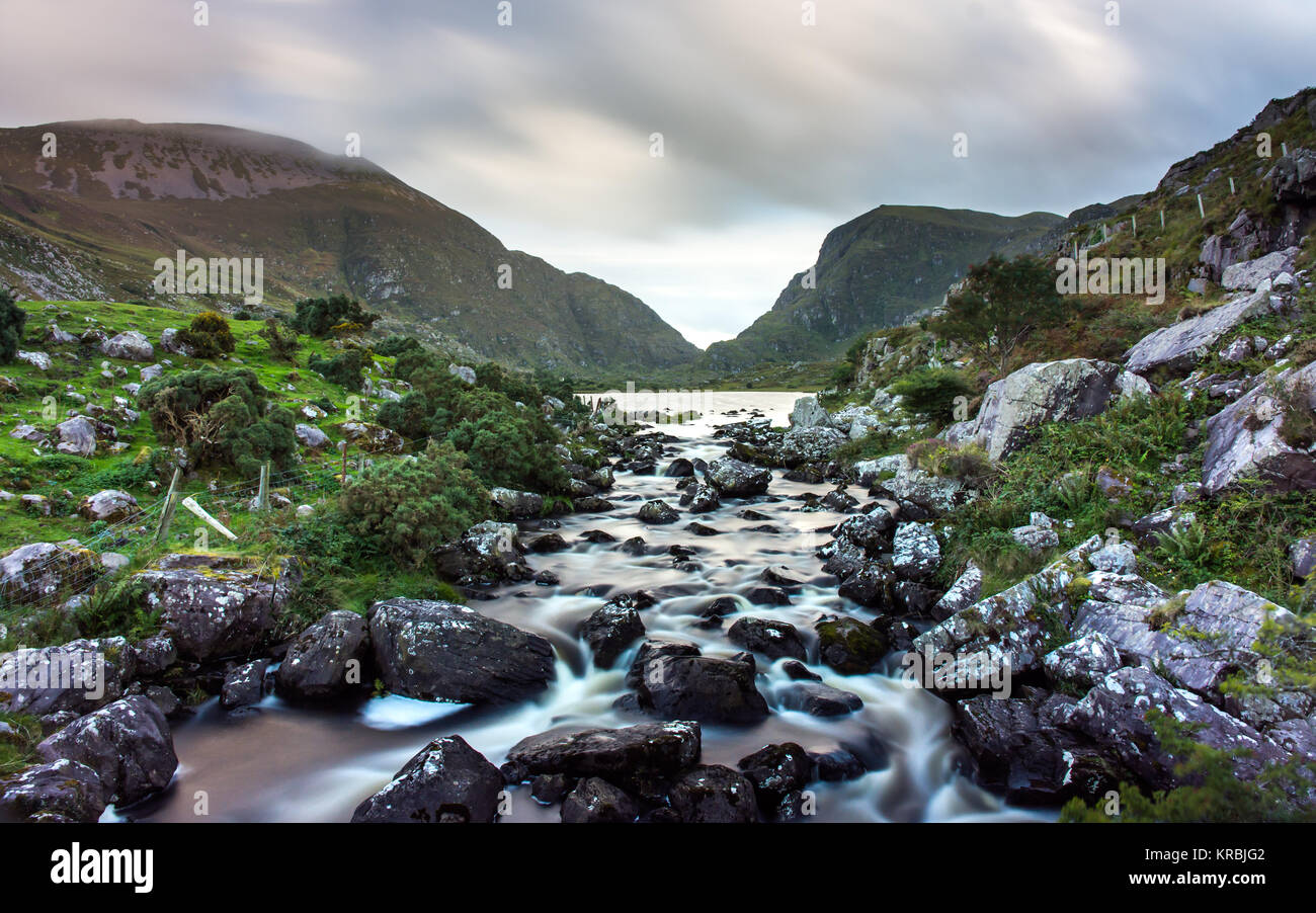 The River Loe tumbles through rocks from the Black Lake in the Gap of Dunloe mountain pass, seen from the Wishing Bridge, in Ireland's County Kerry. Stock Photo
