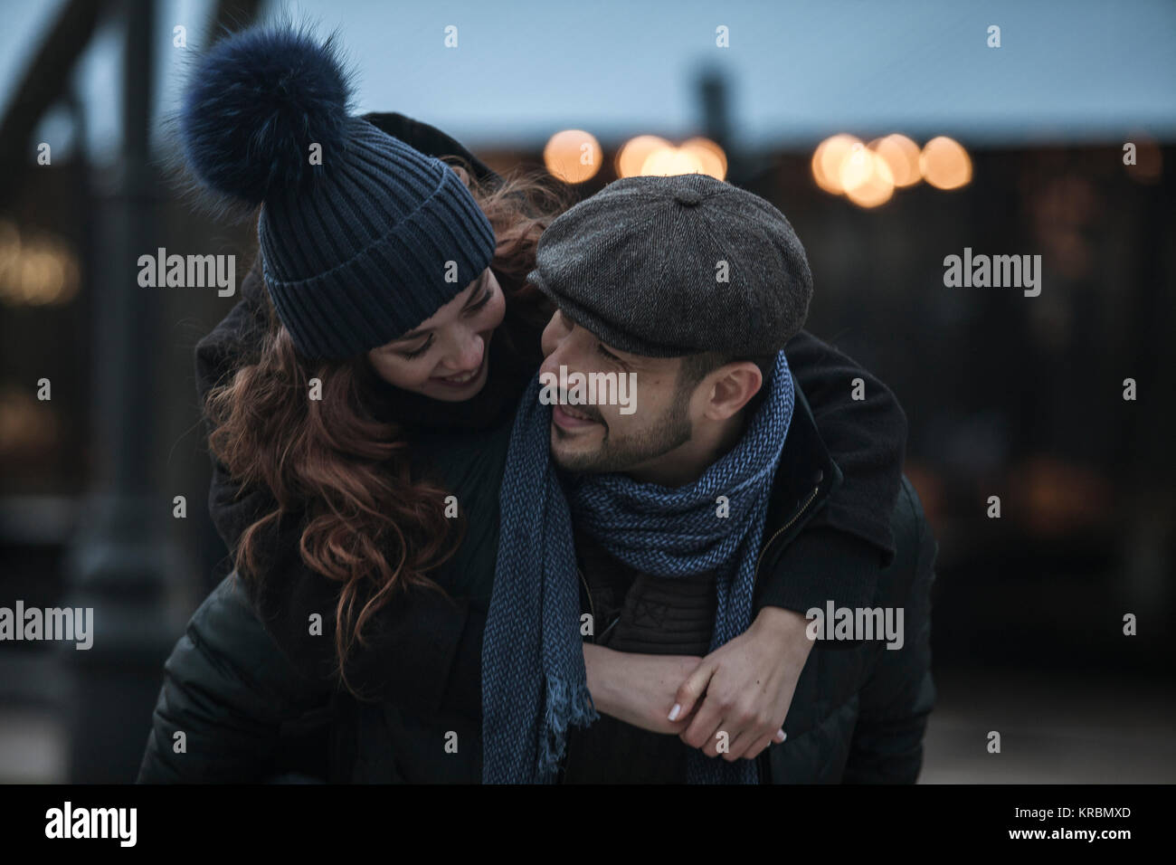Young couple having fun outdoors at winter fair. Wearing warm clothes, hats and scarfs. Visiting christmas market in Vienna, Austria. Everything is de Stock Photo