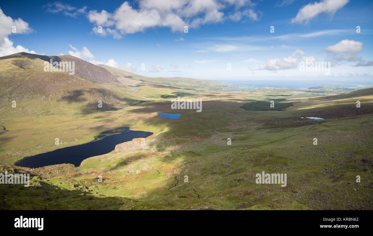Brandon Mountain rises above the lakes of the Owenmore Valley, with Tralee Bay in the distance, forming the spectacular view from the summit of the Co Stock Photo
