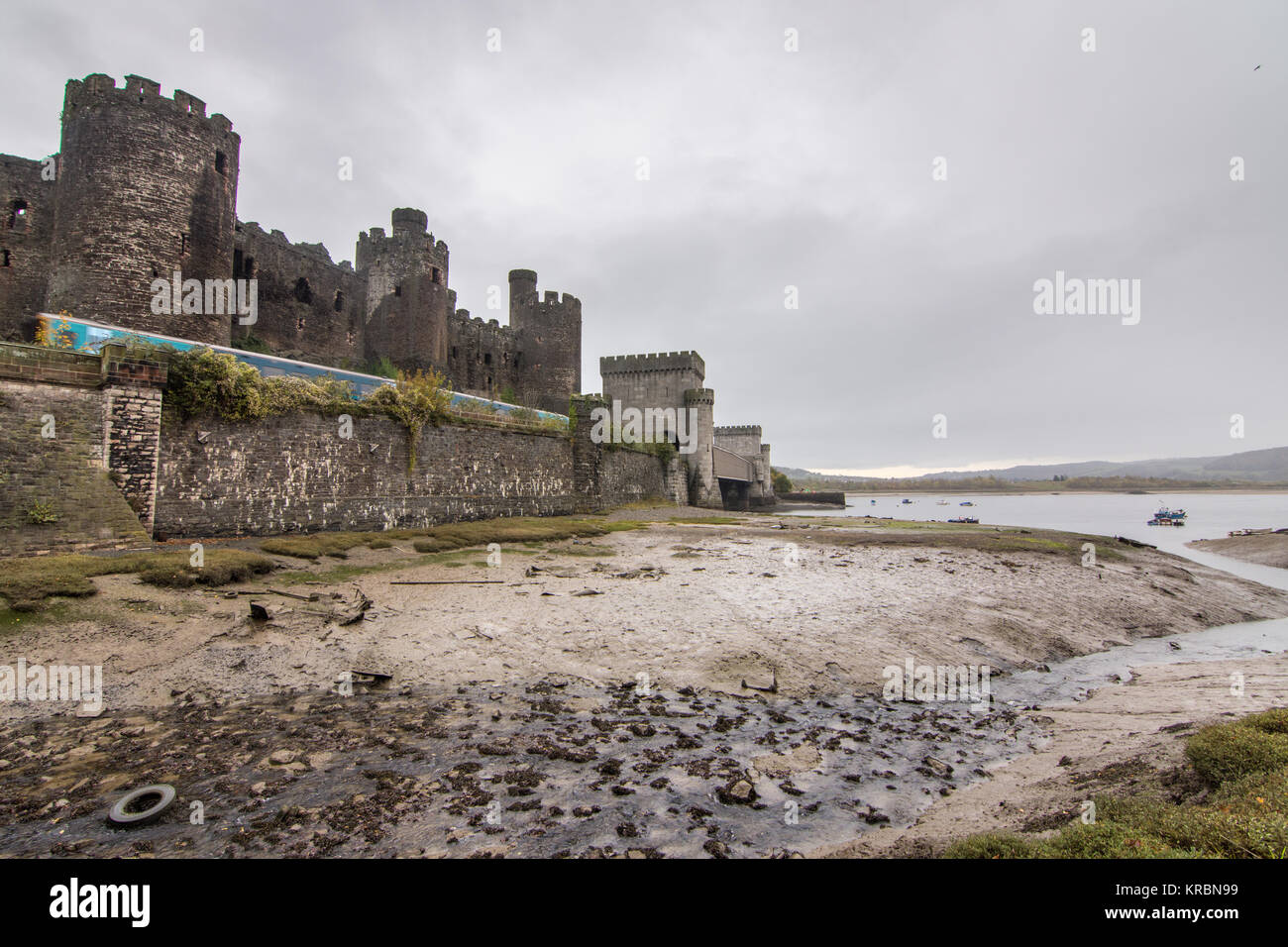 Conwy, Wales, UK - November 5, 2015: An Arriva Trains Wales diesel passenger train passes Conwy Castle on the estuary of the River Conwy in North Wale Stock Photo