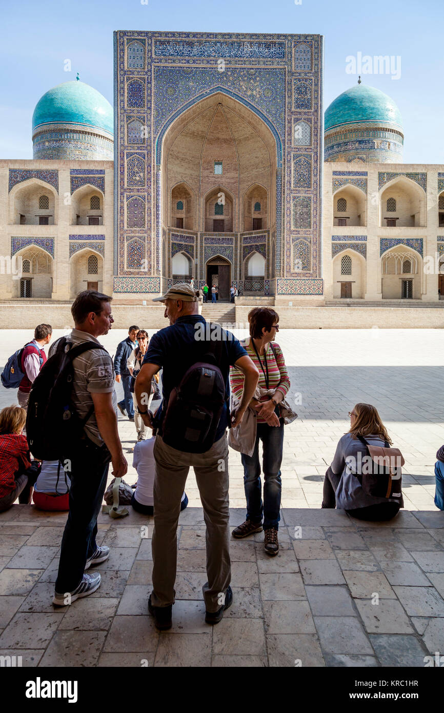 A Group Of Tourists In The Poi Kalyan With The Mir-i-Arab Madrassa In The Backround, Bukhara, Uzbekistan Stock Photo