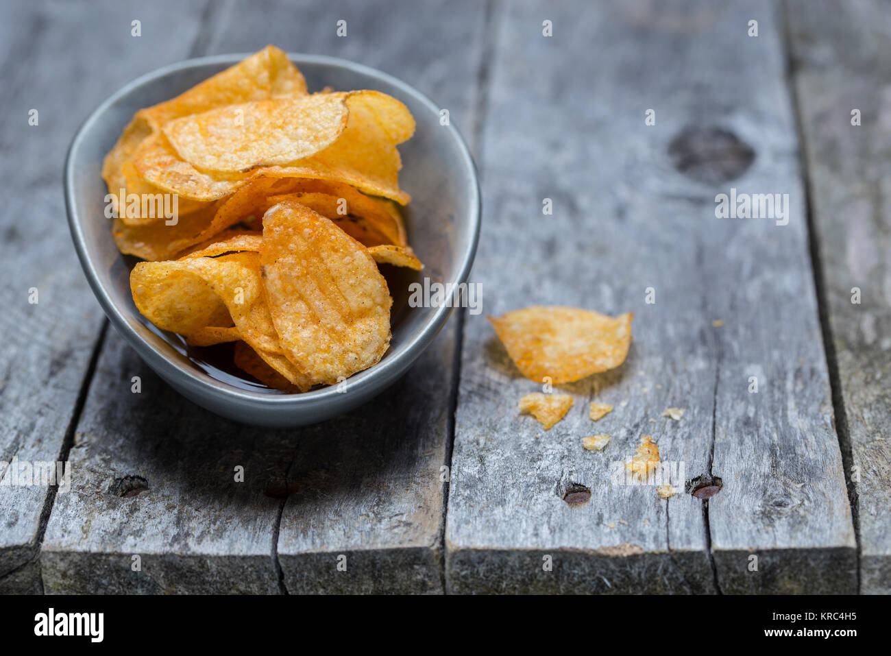 Potato chips on gray rustic wood. Stock Photo