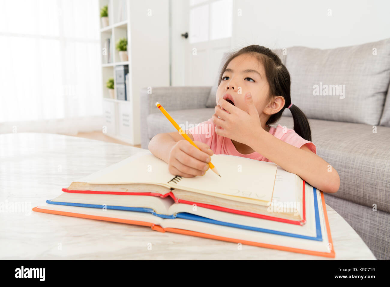 cute young girl student writing school homework feeling tired sleepy and yawning want to rest. Stock Photo