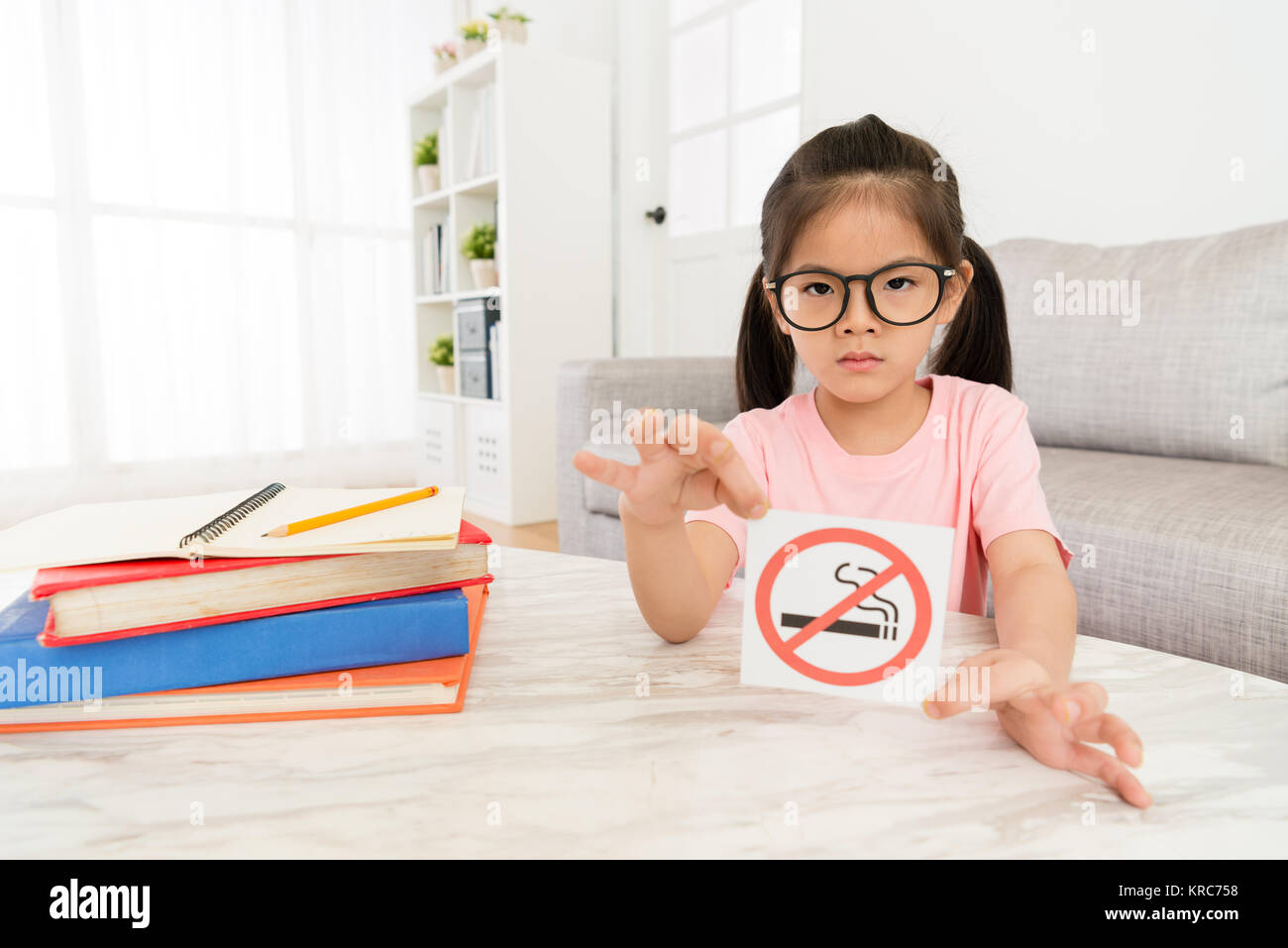 beauty elegant girl kid showing no smoking sign to camera when she doing school studying homework in living room at home. Stock Photo