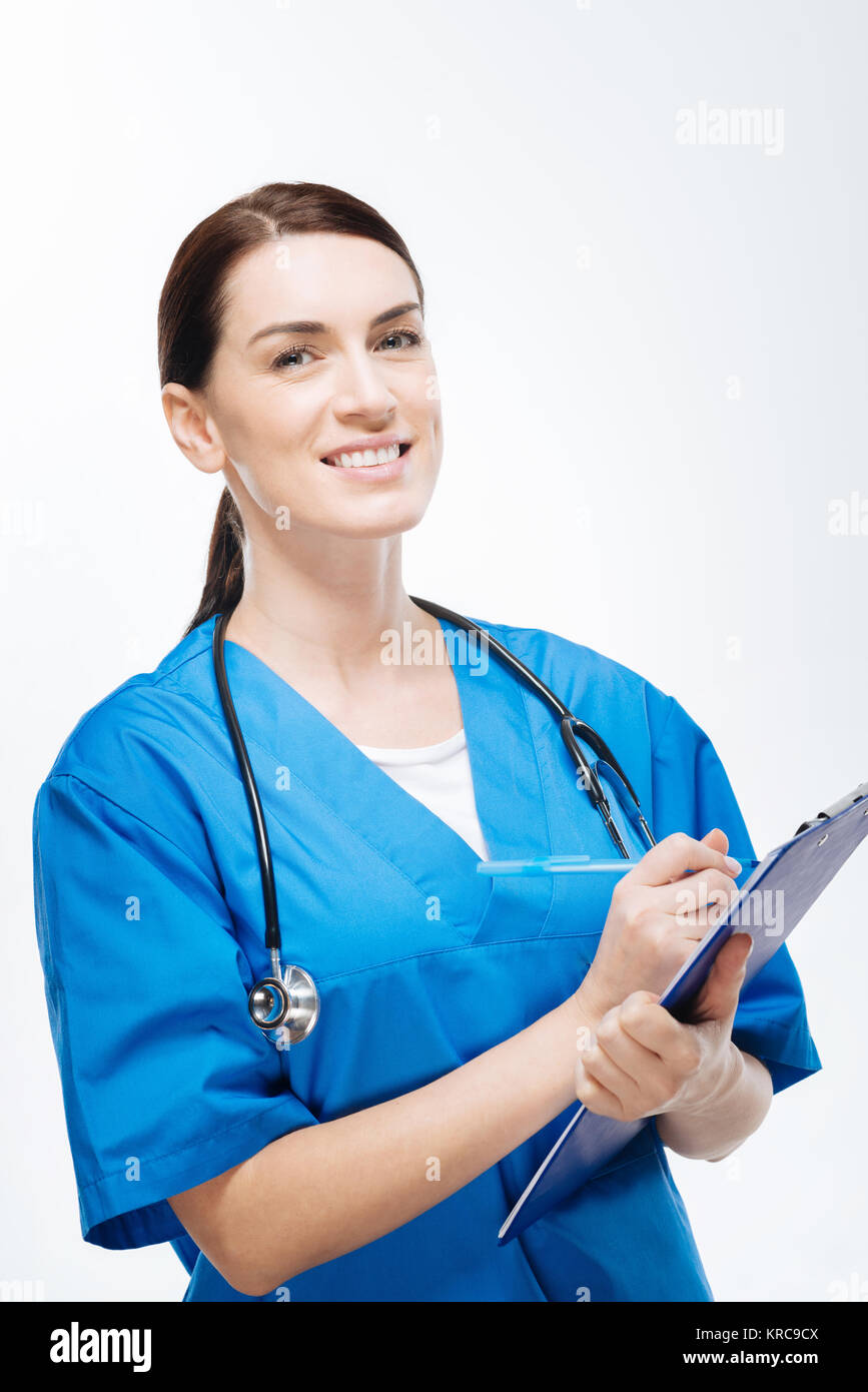 Cheerful female physician writing down family history Stock Photo - Alamy