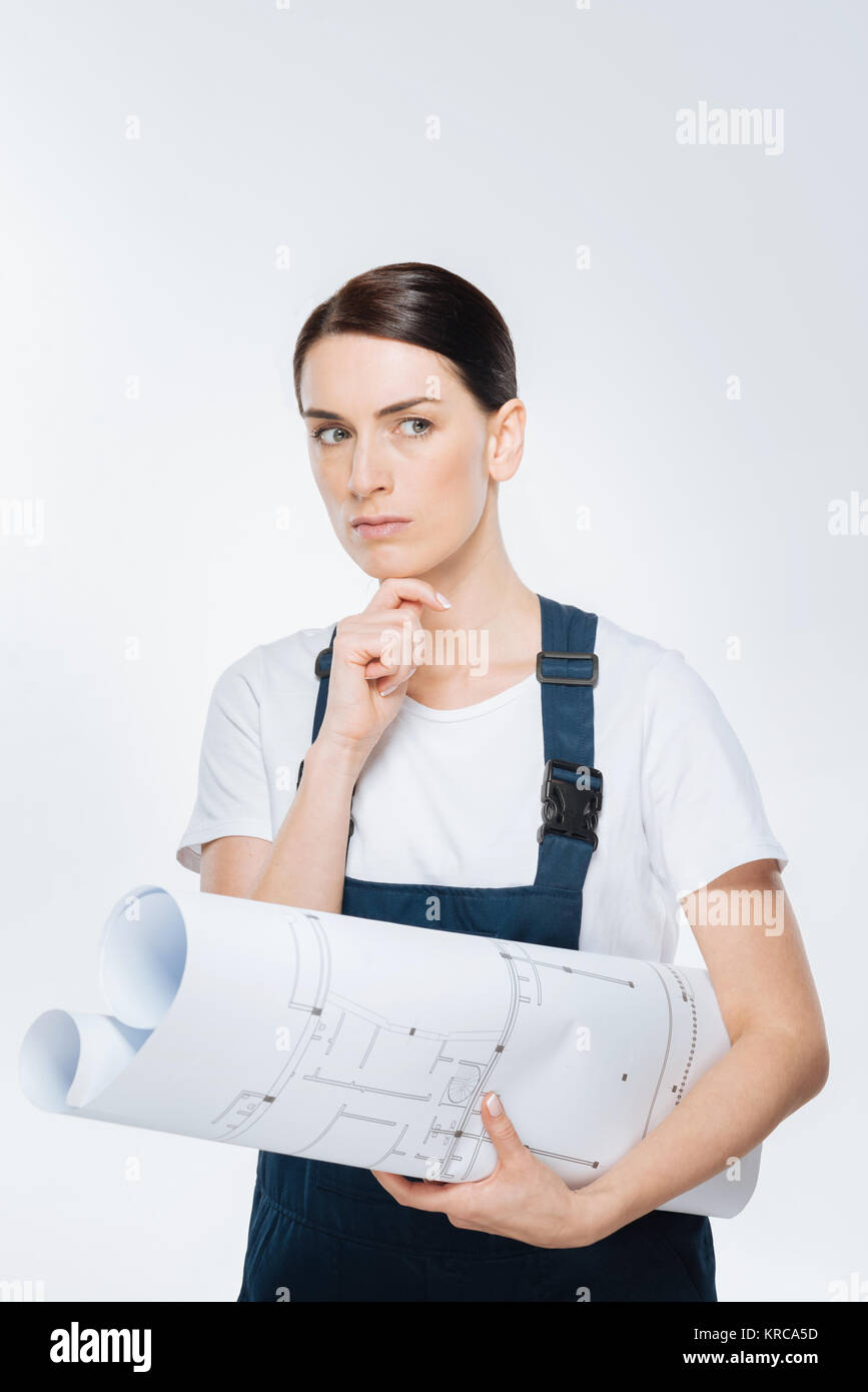 Pensive female architect reflecting about blueprint Stock Photo - Alamy