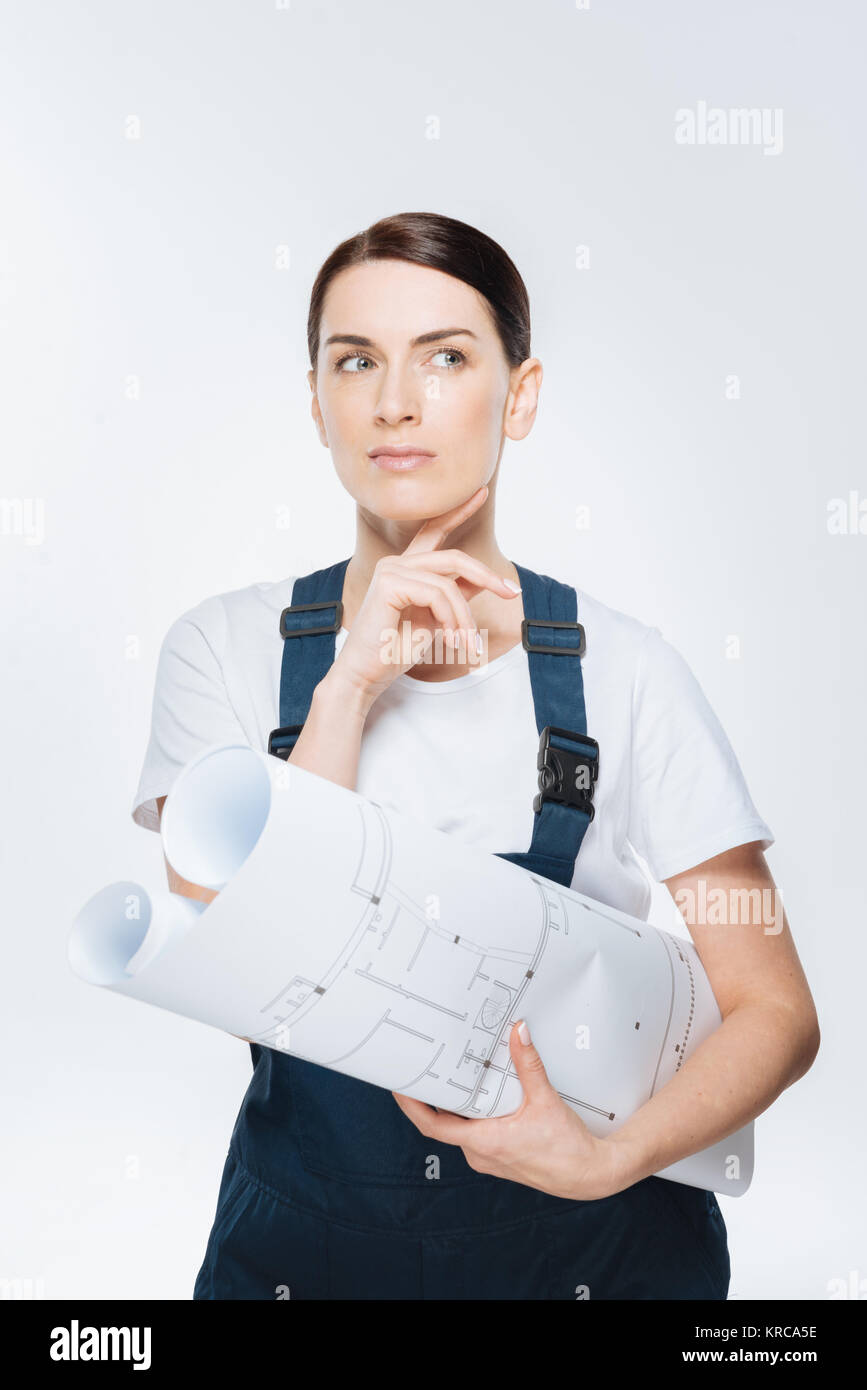 Reflective female architect deciding about blueprint Stock Photo - Alamy