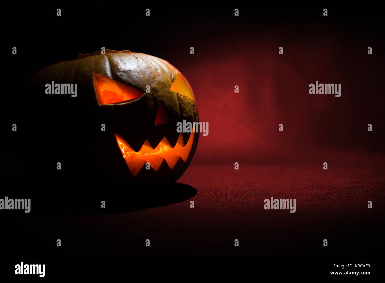 the carved face of pumpkin glowing on halloween on red background Stock ...