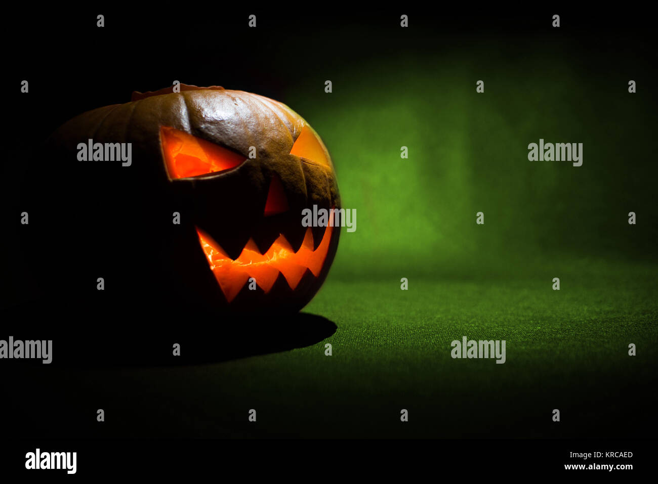 the carved face of pumpkin glowing on halloween on green background ...