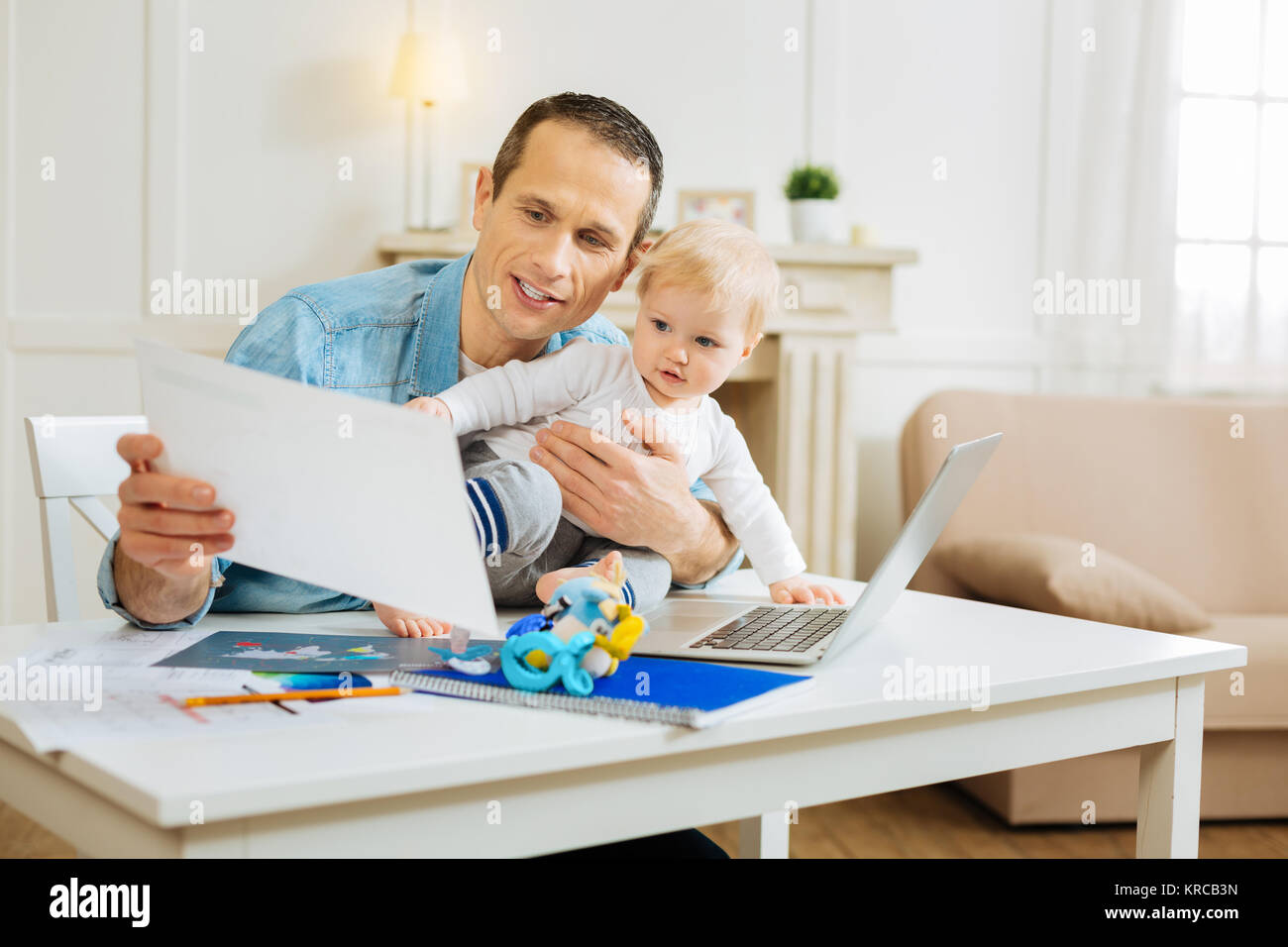 Serious attentive man showing his project to a baby and feeling excited Stock Photo