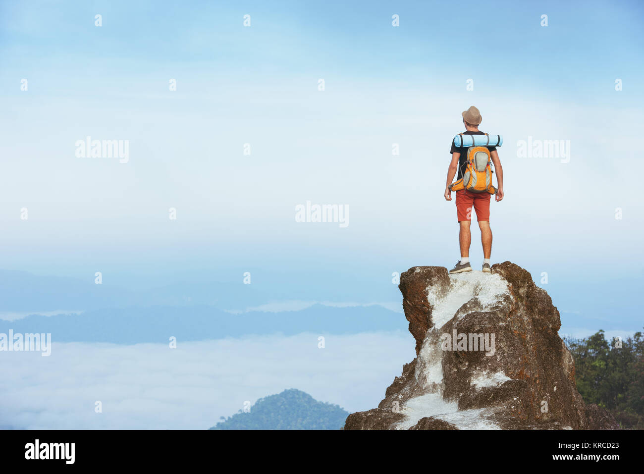 Tourist with backpack at mountain top and misty valley Stock Photo