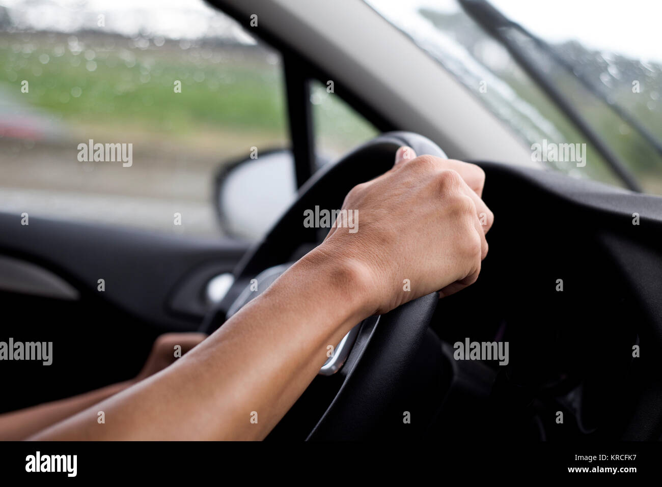 closeup of a young caucasian man driving a car in a rainy day Stock Photo