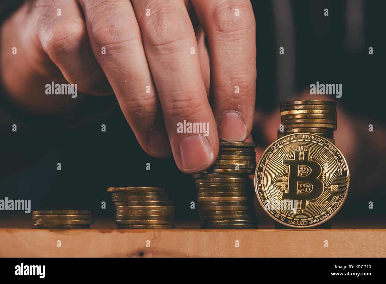 Bitcoin cryptocurrency miner stacking BTC coins, close up of male hand Stock Photo
