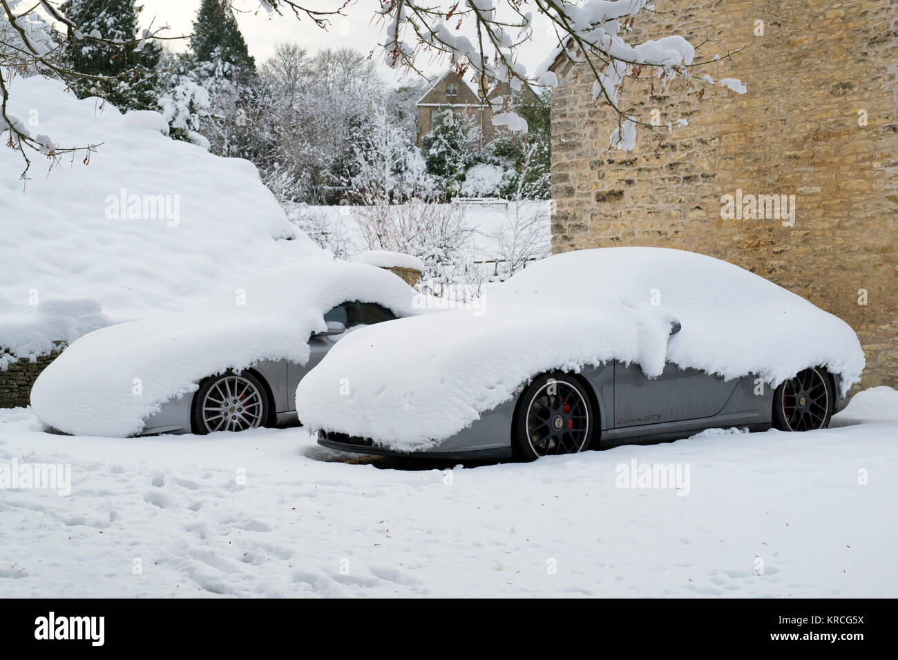 Two porsche cars covered in snow parked in a driveway. Chedworth, Cotswolds, Gloucestershire, England Stock Photo