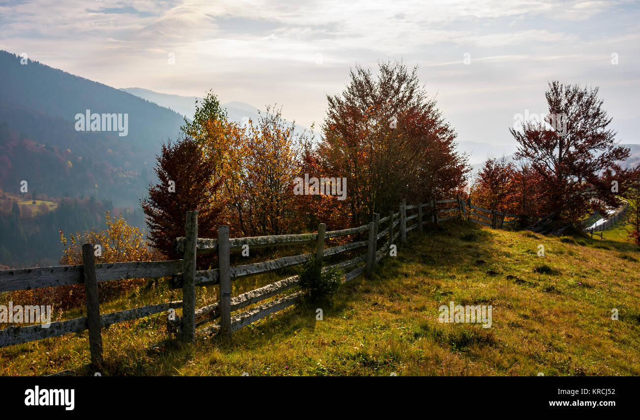 fence along the grassy hillside. beautiful autumn scenery in mountains. calm rural life concept Stock Photo