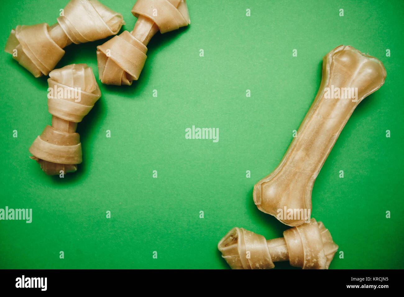 A snack bone and twisted dog treats on a bright onecolor green