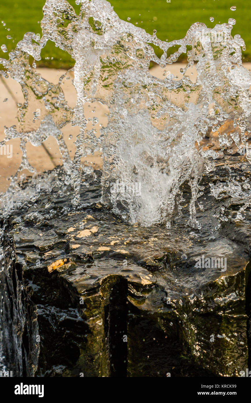 Water fountain out of a black rock in the park Stock Photo
