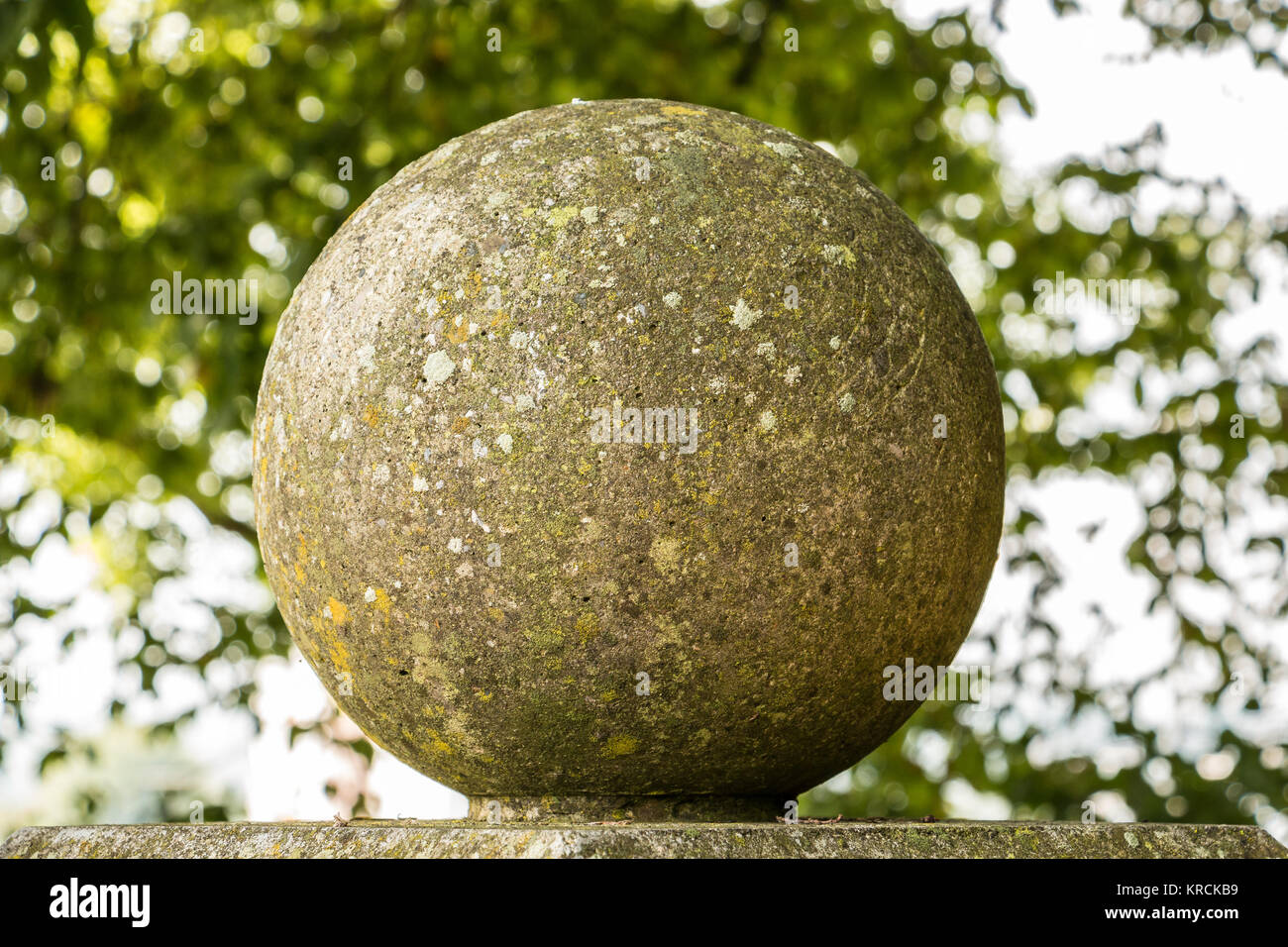 Big stone ball and green leaves in the park Stock Photo