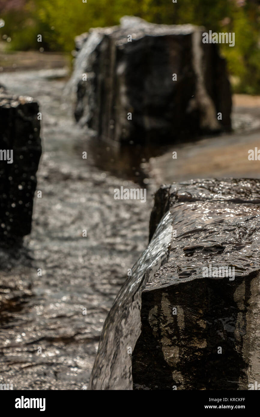 Water fountains out of a black rock in the park Stock Photo