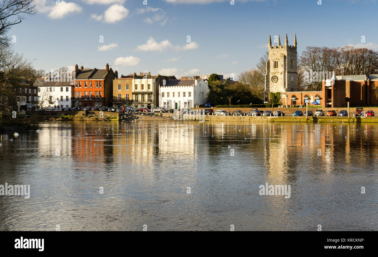 London, England - February 2, 2014: All Saints Church and the terraced houses of Old Isleworth on the River Thames waterfront. Stock Photo