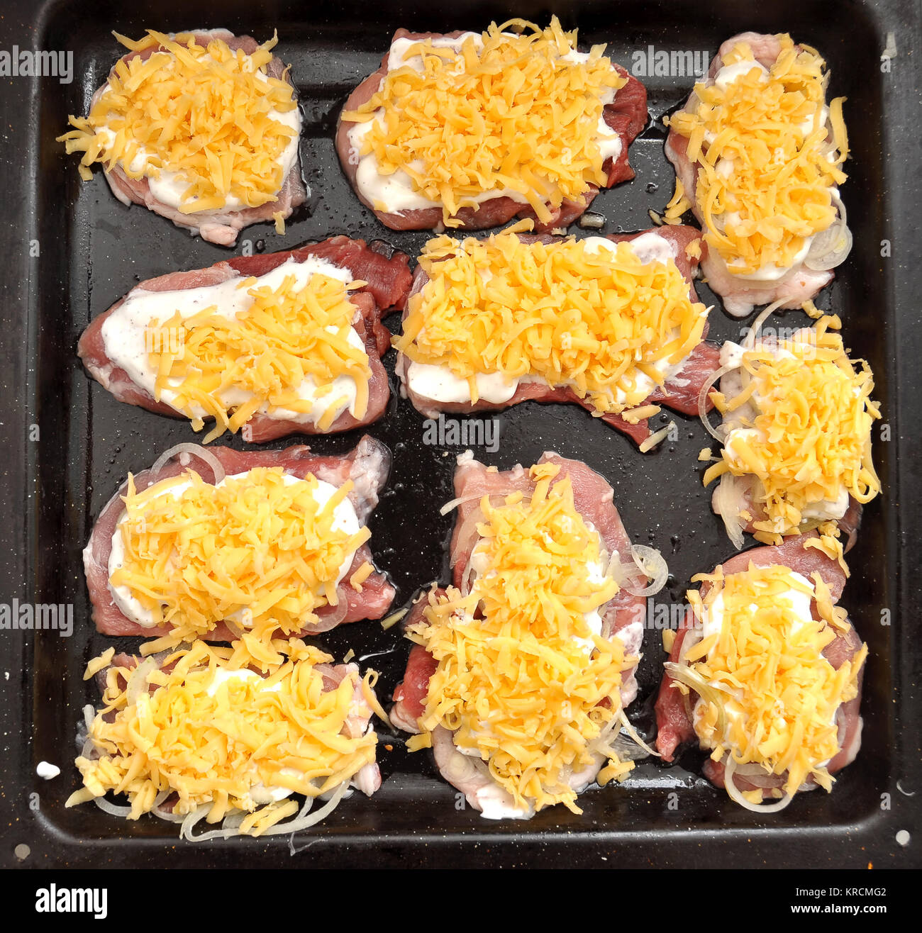 Raw pork chops on a black baking tray. Process of cooking step by step