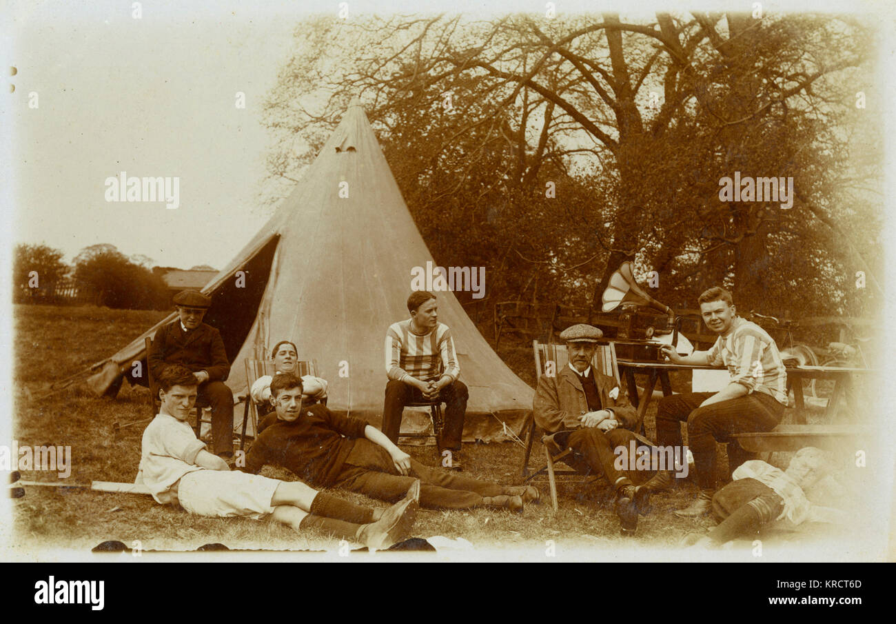 A group of boys and men relaxing on a camping holiday, with a wind-up gramophone to keep them entertained. Date: circa 1905 Stock Photo