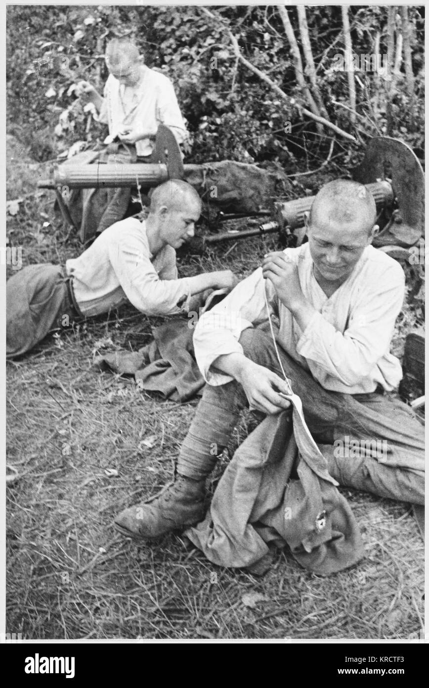 Soviet troops rest behind the front line and make repairs to their uniforms. Date: 1942-43 Stock Photo
