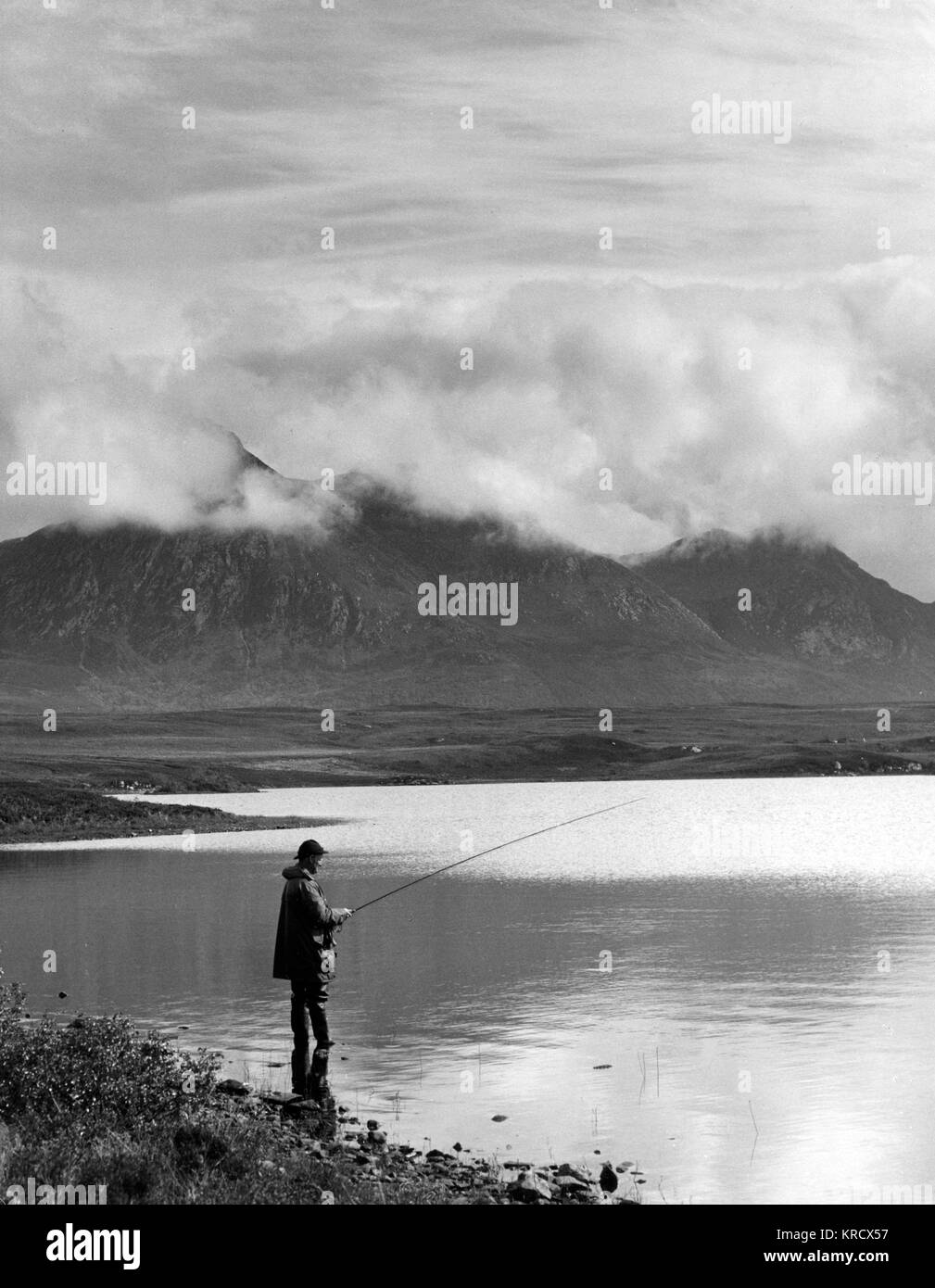 A lone fisherman angling for  trout on Loch Hacoin,  Sutherland, Scotland. A bank  of low cloud hangs over Ben  Loyal in the background.      Date: 1960s Stock Photo
