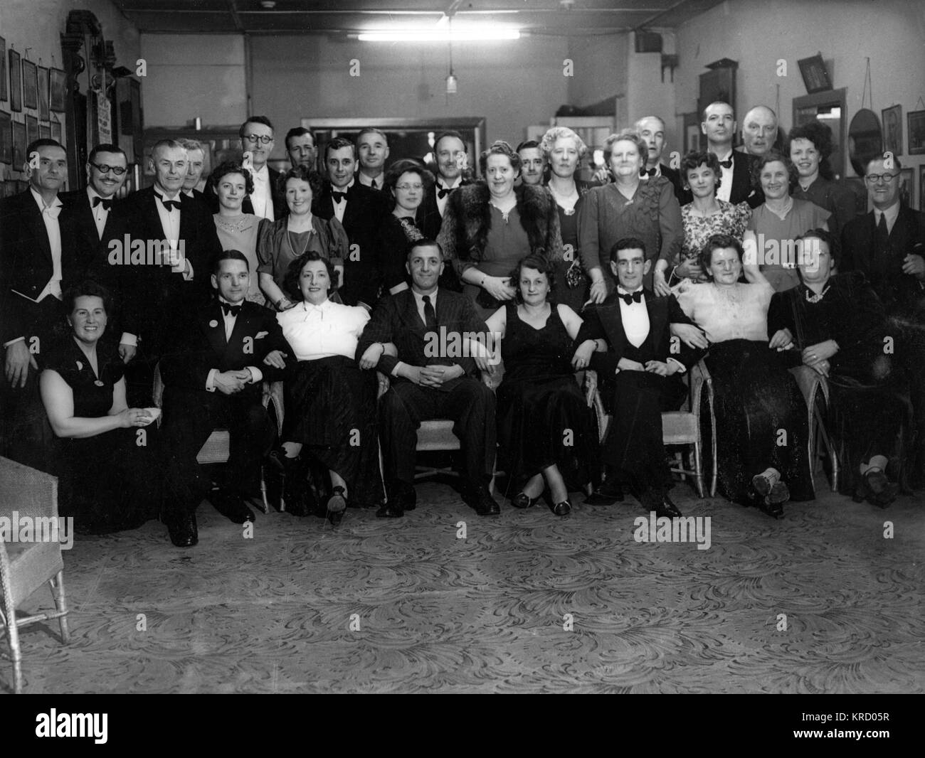 A group of people pose for their photograph.  Most of them are wearing evening dress, no doubt gathered together for a dinner, or a dance, or both!      Date: 1946 Stock Photo