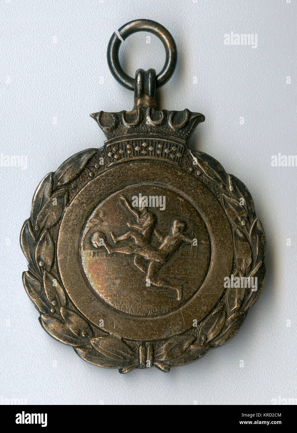 Football medal, with an image of two men playing football at the centre, a crown above, and a laurel wreath design round the edge.       Date: early 20th century Stock Photo