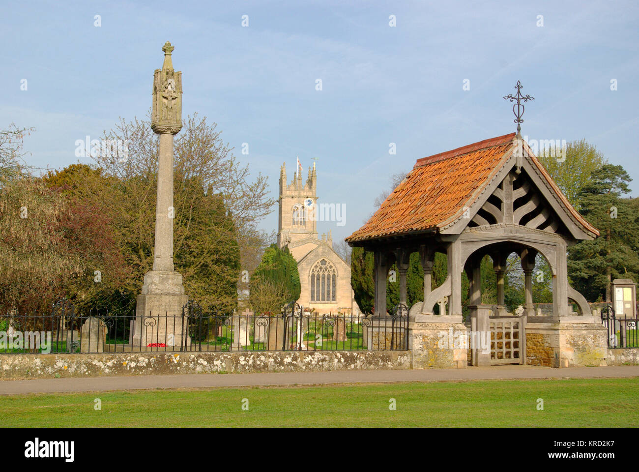 View of St Nicholas' Church, Fulbeck, Lincolnshire, seen from across the churchyard, with a stone cross and a lych gate in the foreground. Stock Photo