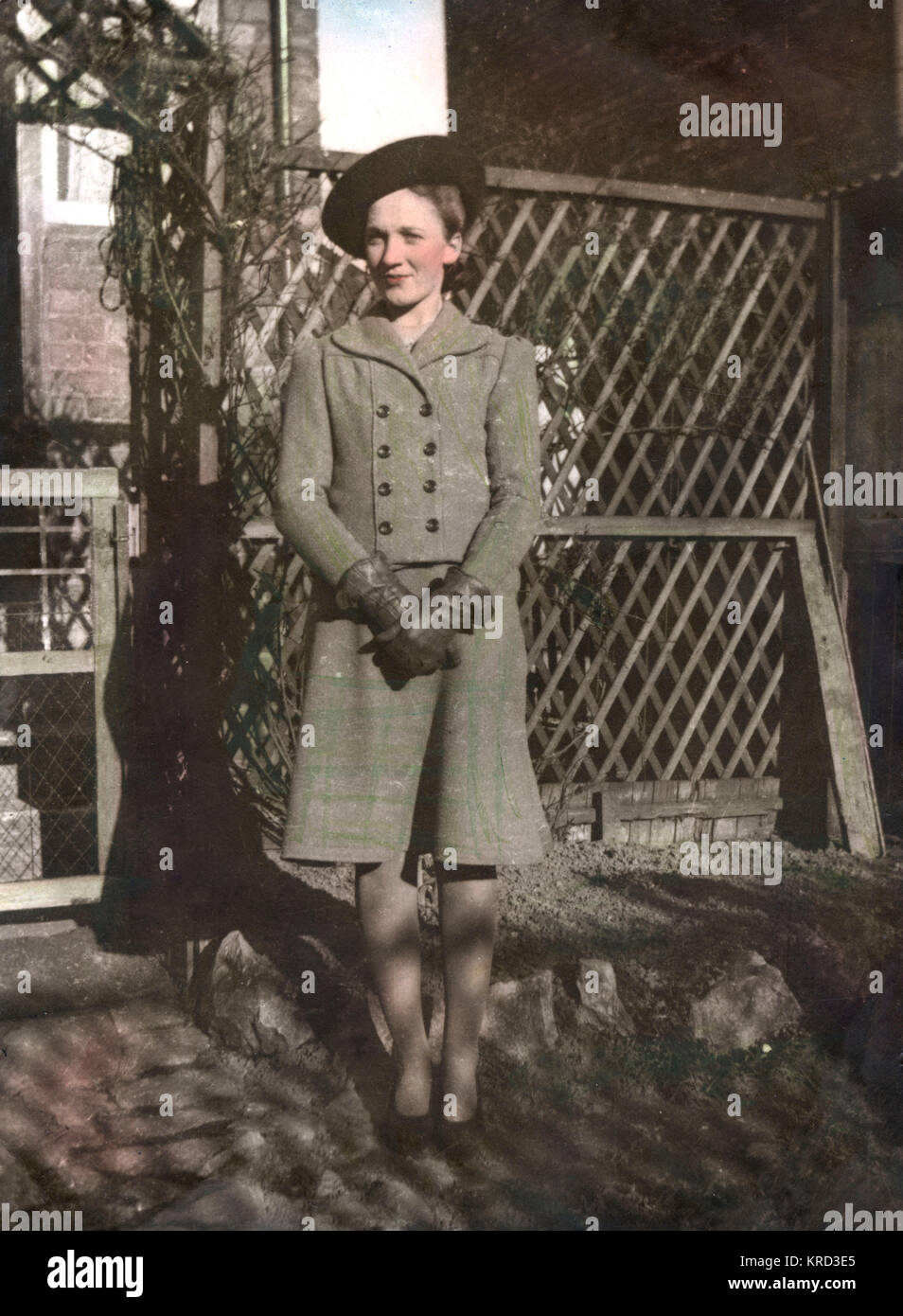 A woman, Dorothy Margaret Hunt (born 1924), poses by a trellis and arch