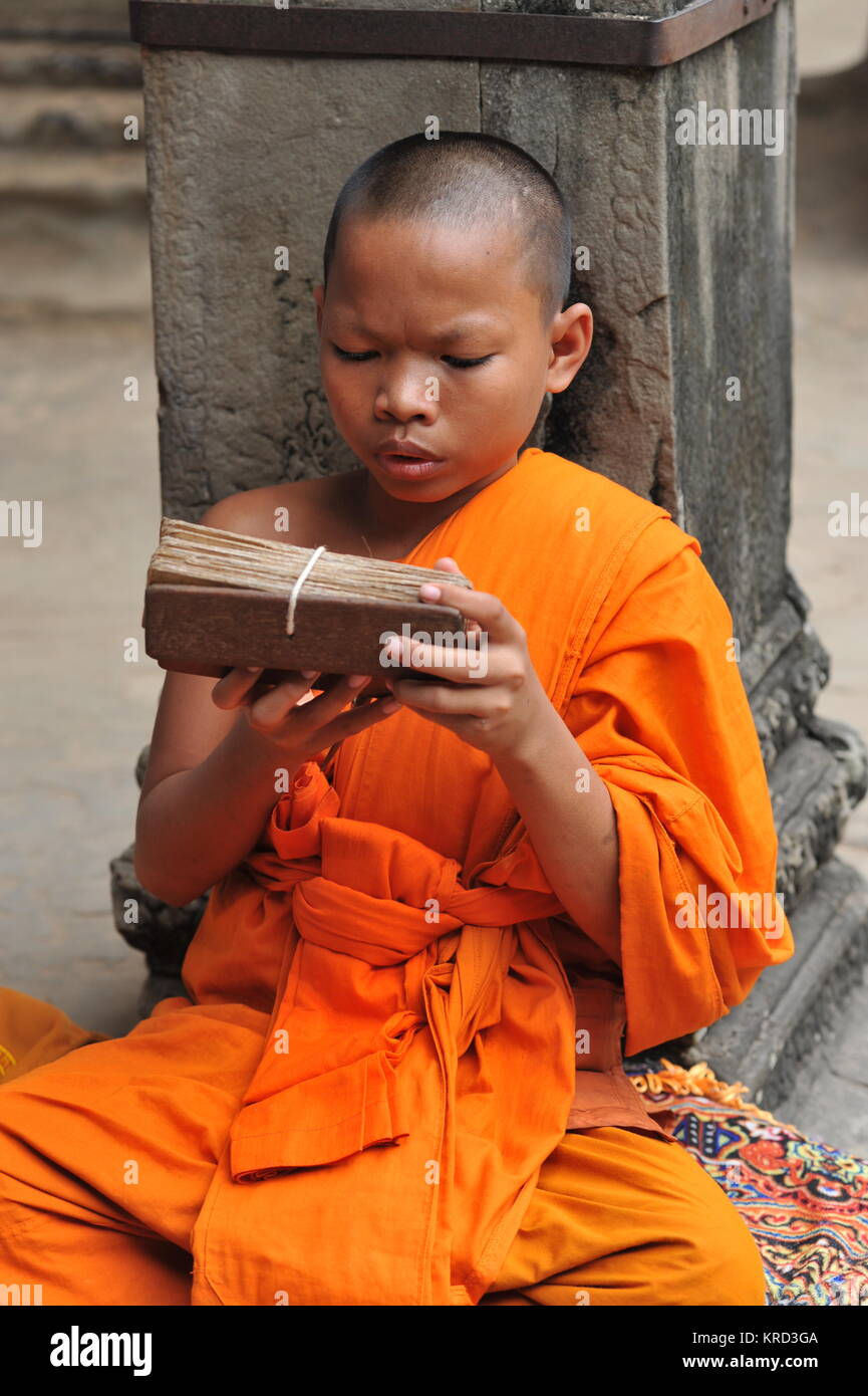 Young Buddhist monk reads from a wooden tablet at Angkor Wat. Siem Reap