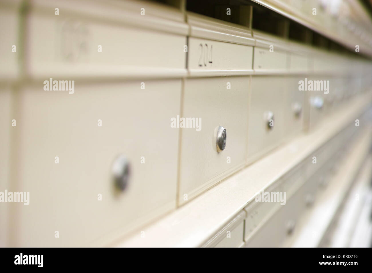 Close-up of a row of cream colored urban mailboxes with numbers, letter slots and individual locks. Letterboxes belonging to a block of flats in Sydne Stock Photo